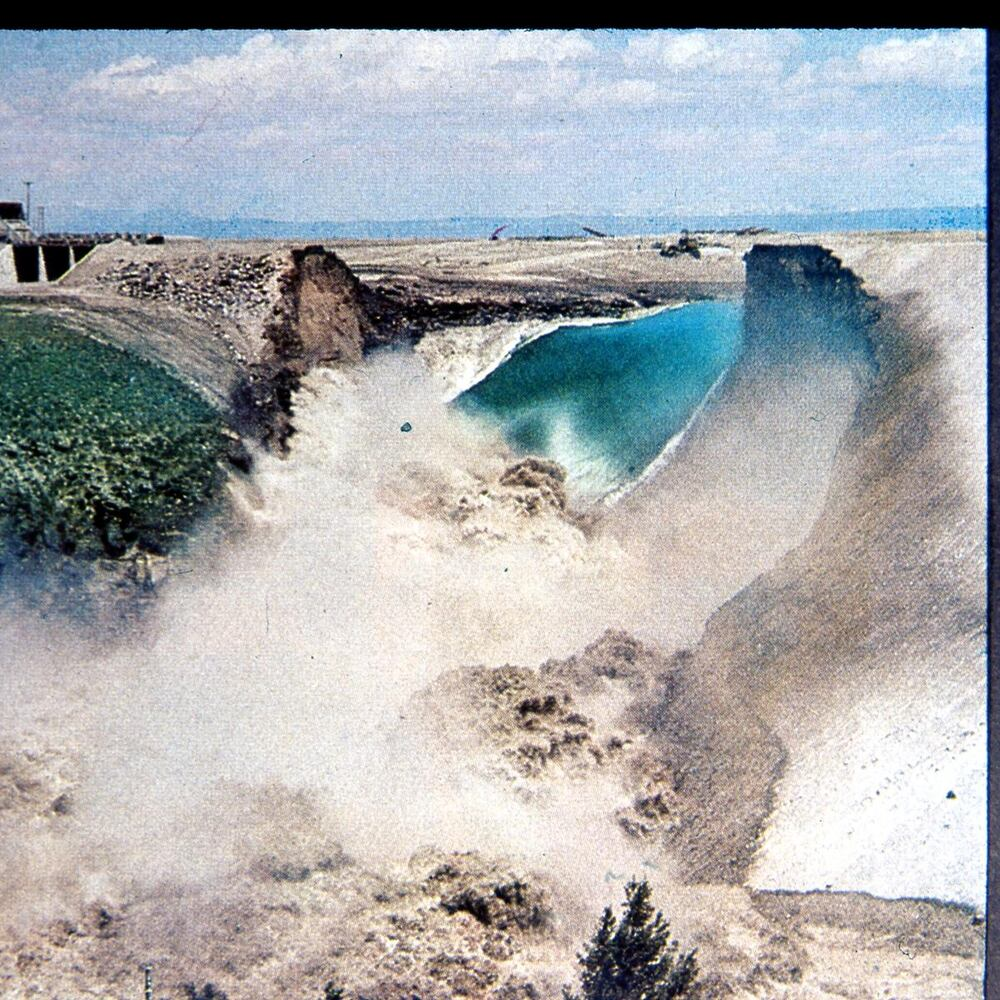 The Teton Dam Failure on June 5, 1976. Water can be seen flowing out of the reservoir and through the failed dam.